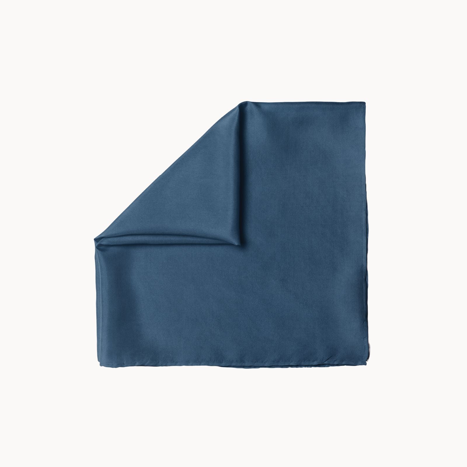Folded square silk headscarf in a cool blue lagoon tone, offering a smooth, fluid texture with a refined satin finish, elegantly positioned on a white background.