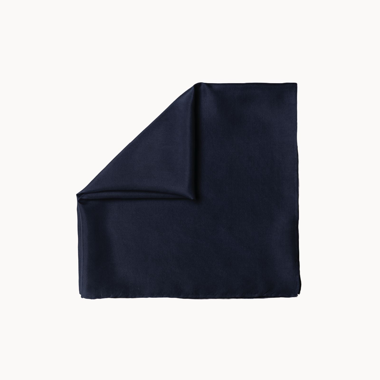 Folded square silk headscarf in a deep midnight sail navy tone, presenting a smooth, refined surface with a subtle glossy finish, laid flat on a white background.