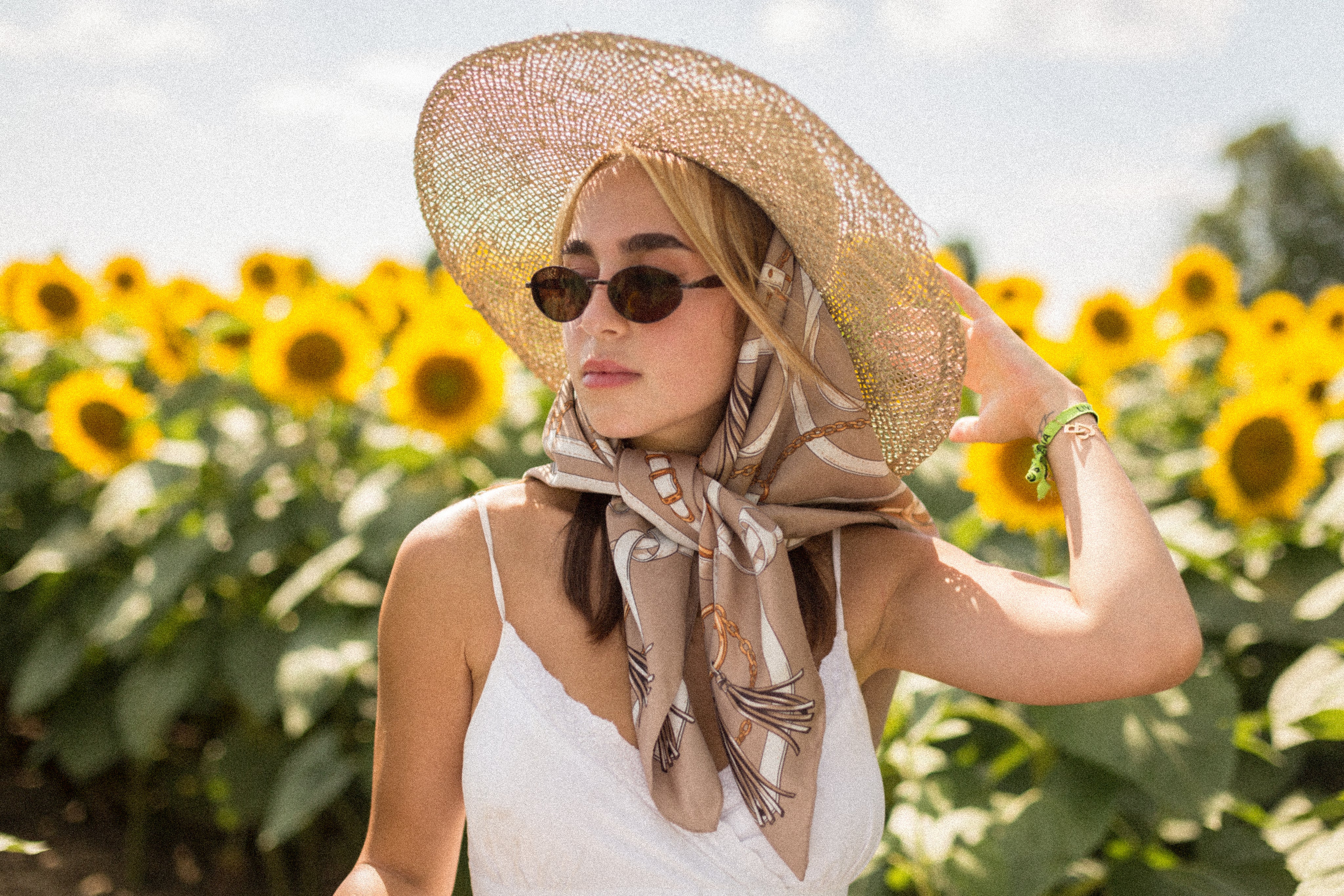 woman-wearing-a-silk-scarf-stands-in-a-field-of-sunflowers.jpg